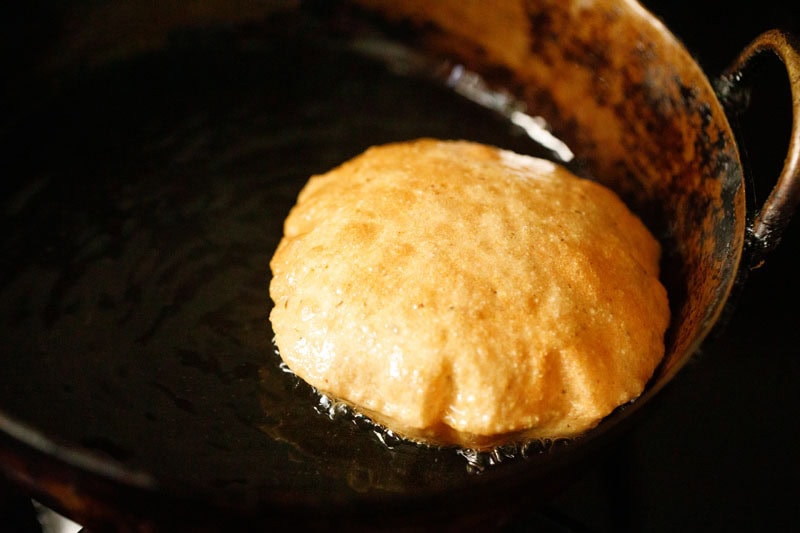 fully puffed poori floating in oil.