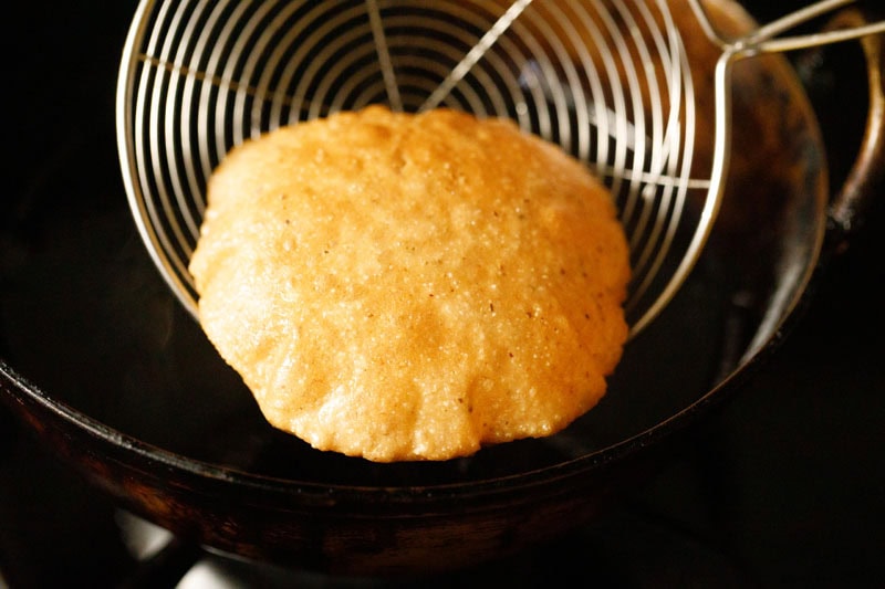 bedmi poori lifted with a spiral spoon.