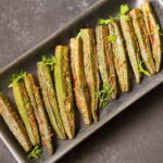 bharwa bhindi garnished with coriander leaves and served on a long platter.