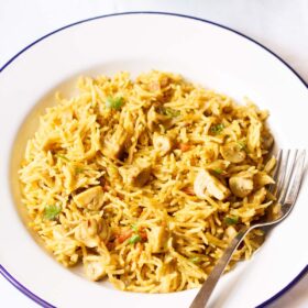 chettinad biryani on a blue rimmed white plate with a fork.