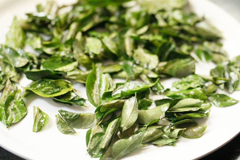 crispy roasted curry leaves on a white plate.