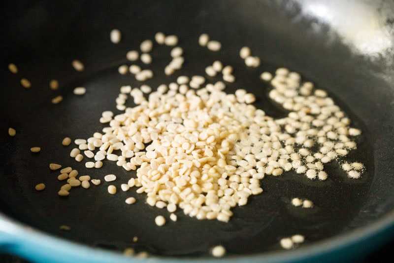 raw white urad dal in skillet.