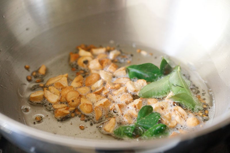 curry leaves and asafoetida in the pan together with the golden cashews and spices.