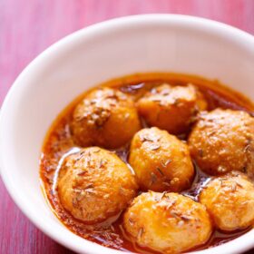 kashmiri dum aloo served in a white bowl on red wooden tray.