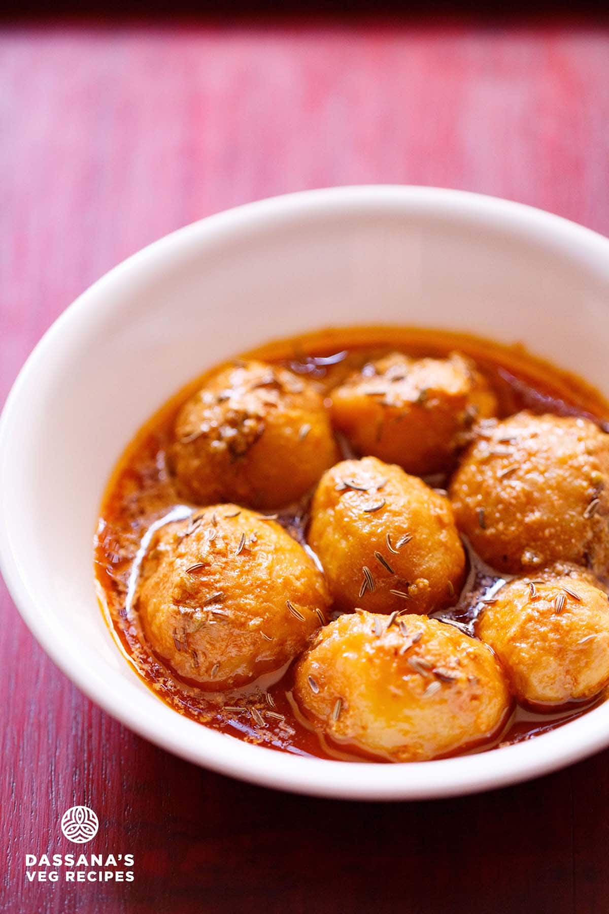 kashmiri dum aloo served in a white bowl on red wooden tray.