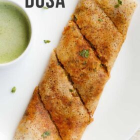 folded paneer dosa garnished with a few coriander leaves alongside a bowl of green colored coconut chutney with text layovers.