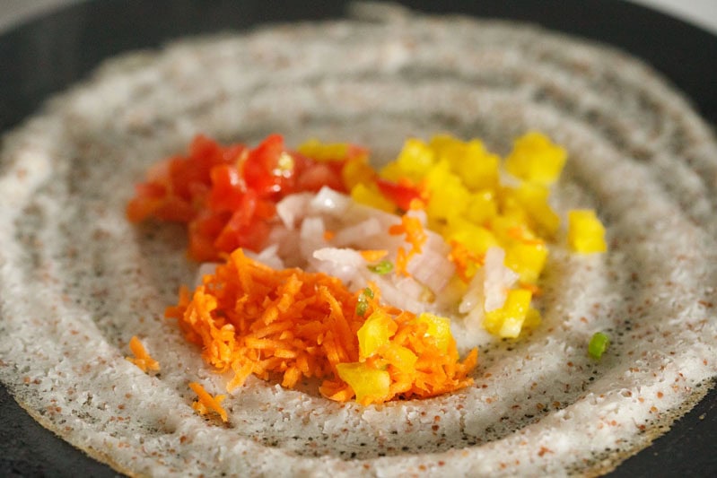 veggies on dosa on a skillet (tawa).