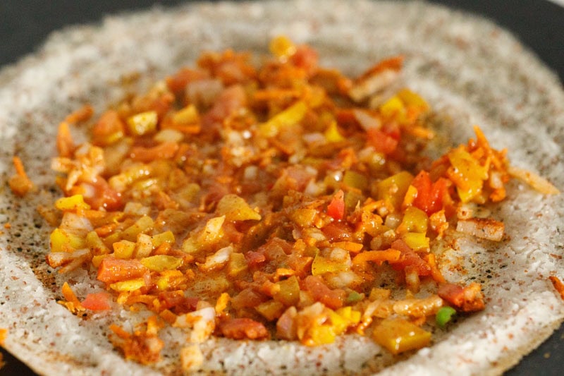 spices, herbs mixed with vegteables and spread in a single layer on dosa.