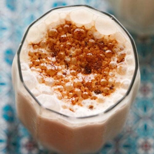 overhead shot of Sharjah Shake with a sprinkling of Bournvita on a blue design tray.