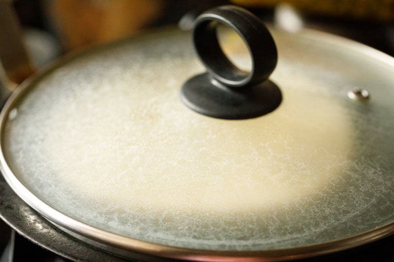 rolled dough disc on the tawa, covered with glass lid with a handle.