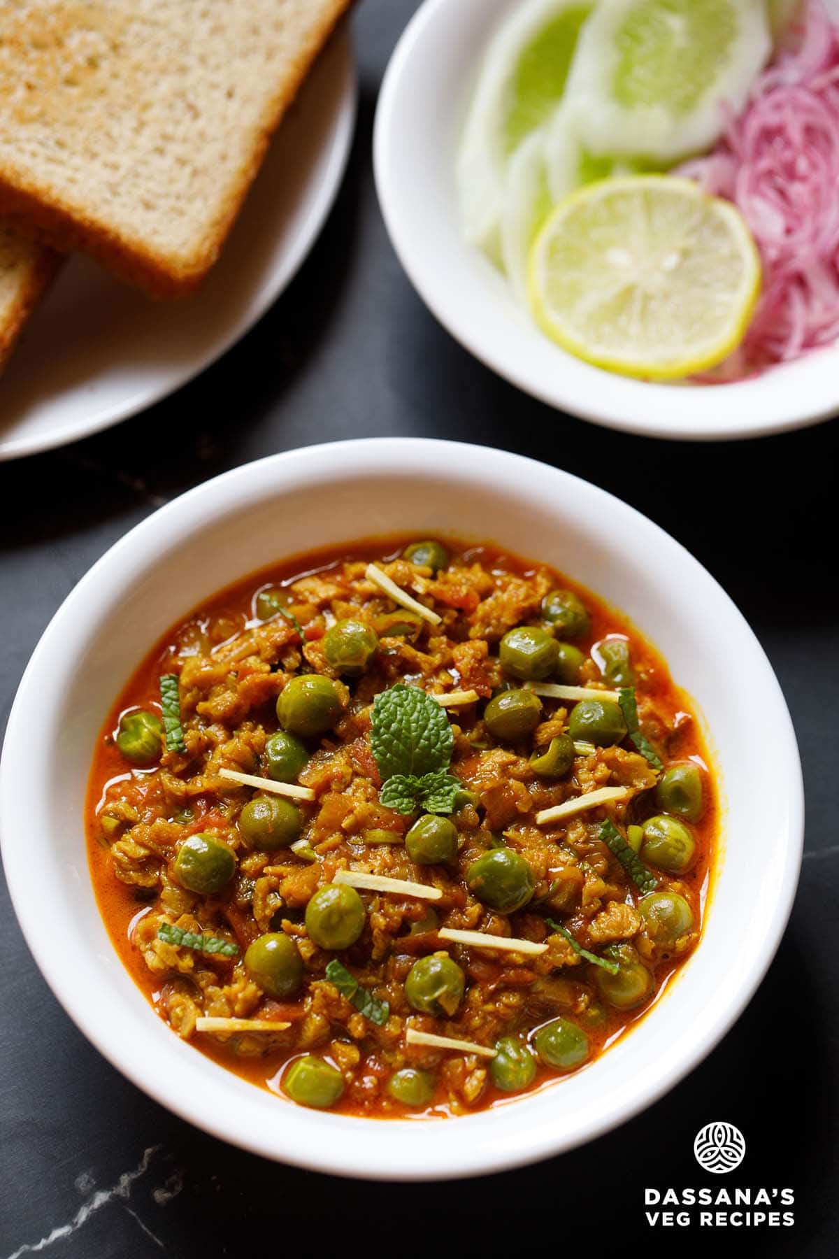 soya keema in a white bowl with bread and sliced onions, cucumber and lemon slice.