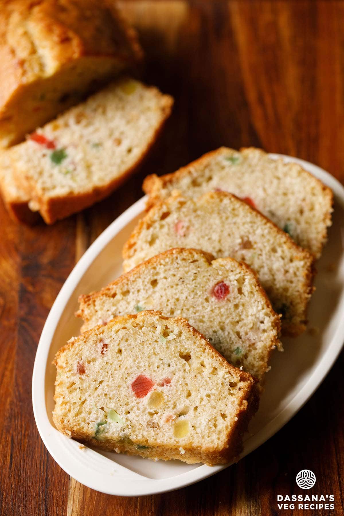 four slices of eggless tutti frutti cake served on a white plate.