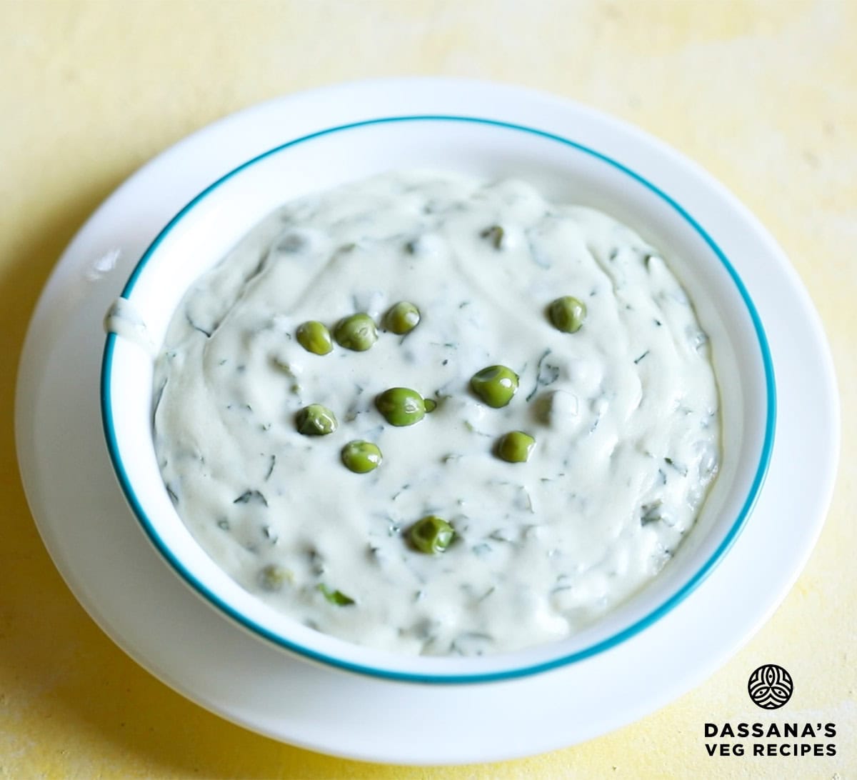 methi matar malai in a white bowl with a light blue rim, garnished with a few peas.