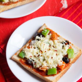 two white serving dishes, each with a slice of bread pizza on a red table with a red cloth underneath.