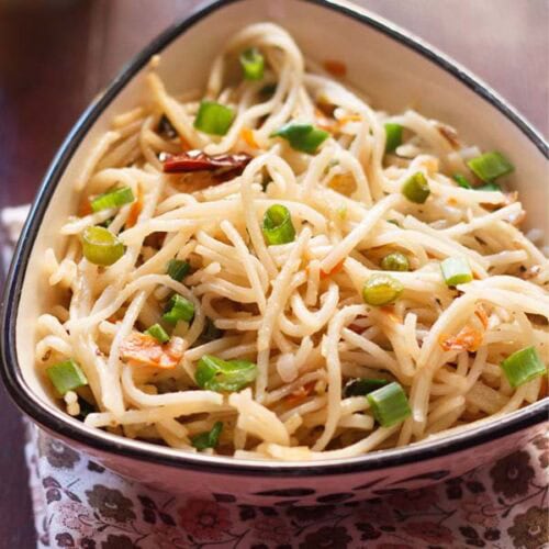 hakka noodles garnished with chopped spring onion greens and served in a triangular bowl on a printed napkin.