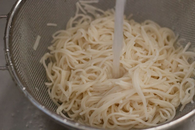 rinsing cooked hakka noodles with fresh water. 