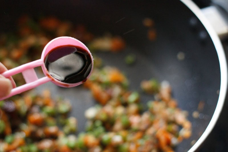 adding soy sauce to vegetables.