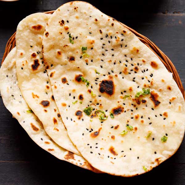 three naan stacked on a cane basket.