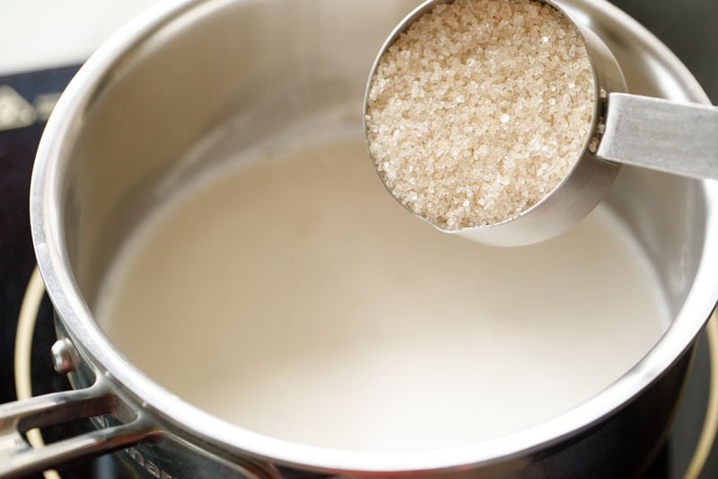 sugar being added to hot water for making cocoa solution. 