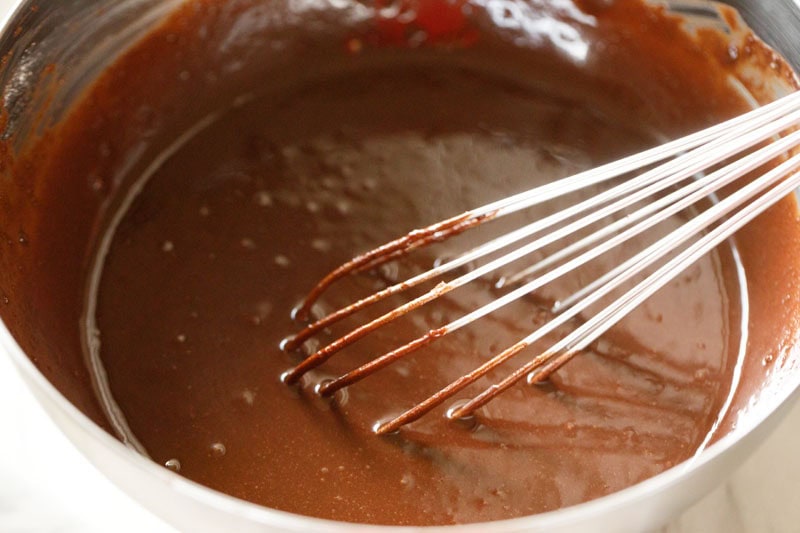 mixing ingredients with a wired whisk for eggless brownie.